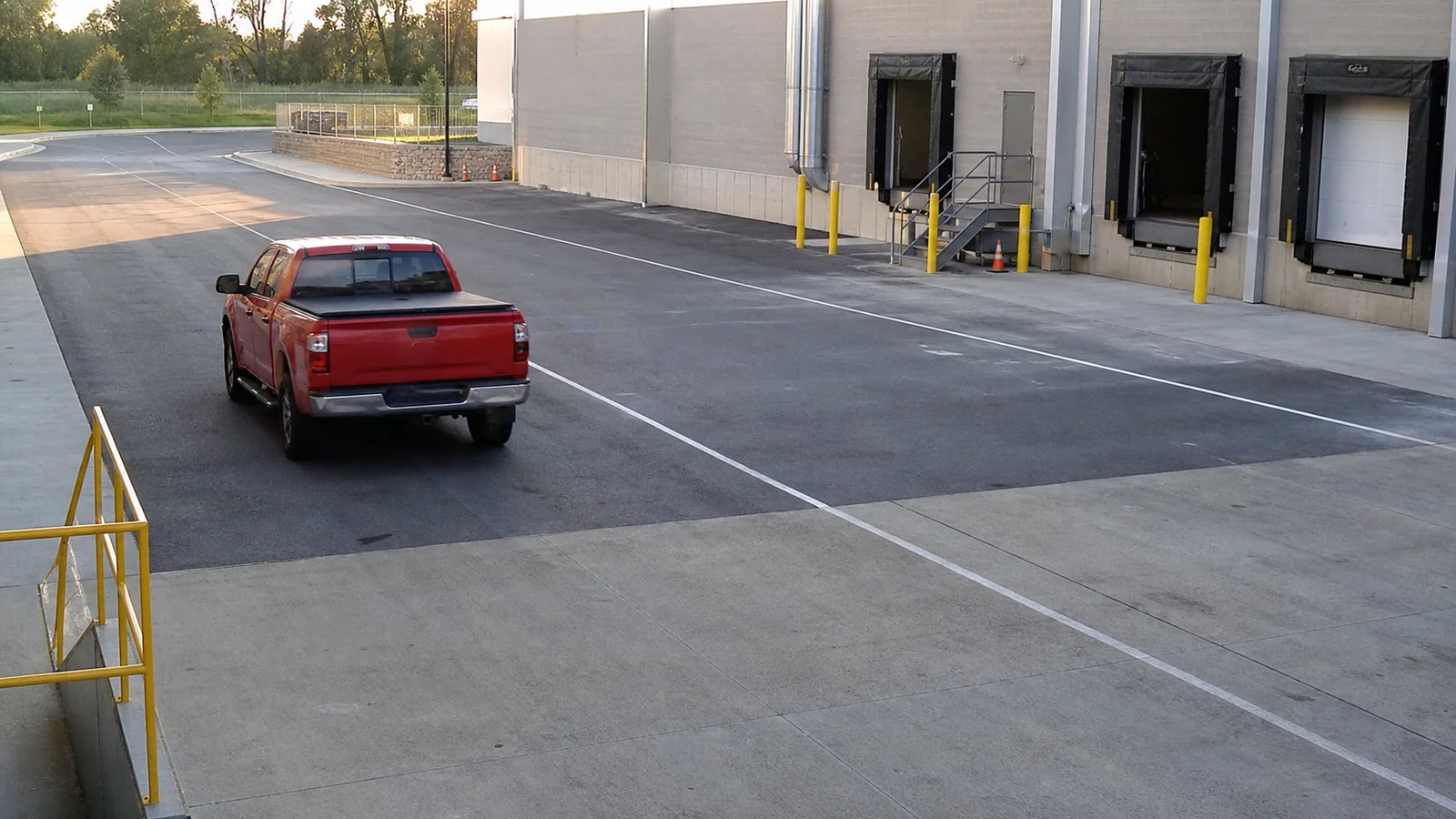 Simulated loading dock security-camera view showing a red pickup truck departing